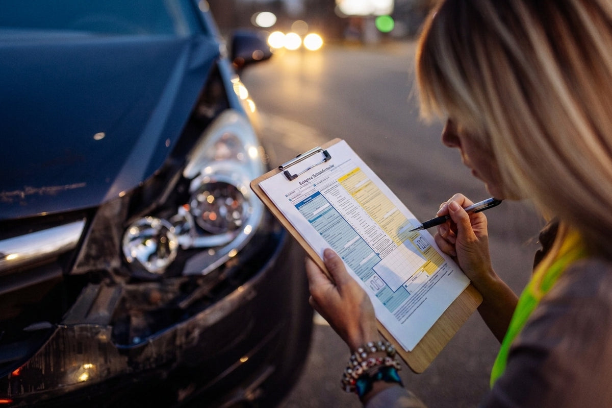 Vrouw vult een Europees schadeformulier in op een klembord naast een beschadigde auto
